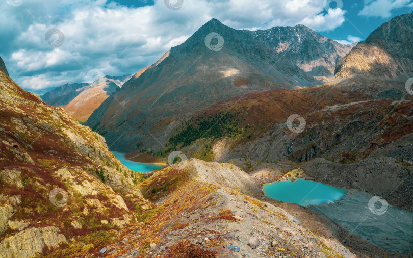 Скачать Панорамный вид на пеструю горную долину с лазуритовыми озерами. Живописный горный пейзаж с разноцветными остроконечными скалами. Красочный горный пейзаж с острыми скалами и многоцветной горной долиной. фотосток Ozero