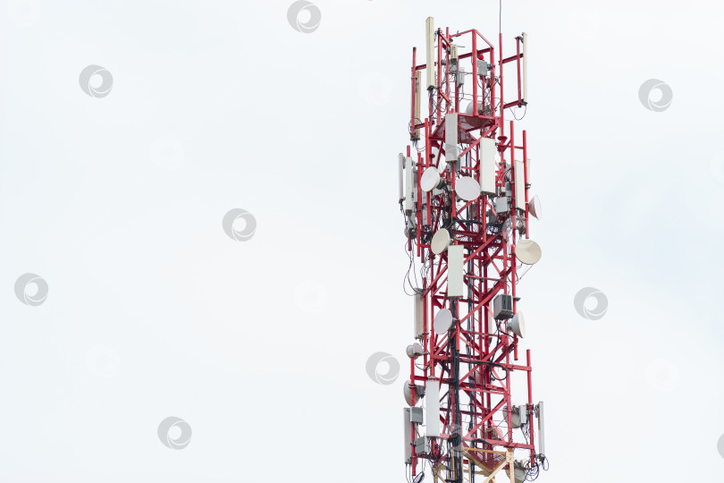 Скачать верхняя часть радиовышки с установленными антеннами и другим оборудованием на фоне белого облачного неба фотосток Ozero