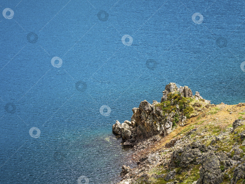 Скачать Красивый природный фон каменистого дна в бирюзово-прозрачной воде ледникового озера при солнечном свете. Солнечный фон с множеством камней в зеленой прозрачной воде ледникового озера. фотосток Ozero