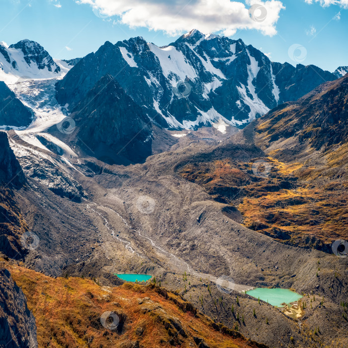 Скачать Потрясающий альпийский панорамный вид с перевала на горную долину в солнечном свете и великолепные силуэты гор на горизонте. Красочный зеленый пейзаж с силуэтами больших скалистых гор и эпическим глубоким ущельем. фотосток Ozero