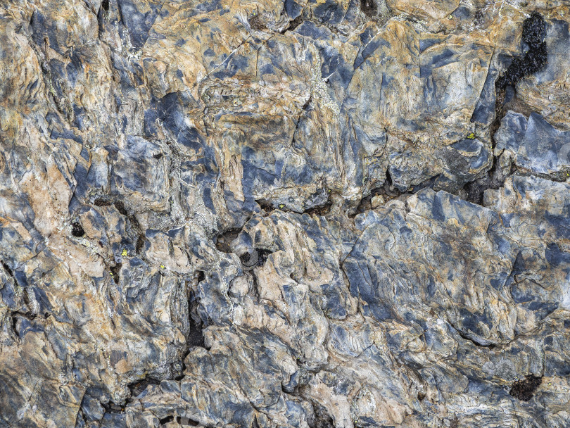 Скачать Волнистая текстура камня. Разноцветная детализированная текстура скалистого горного склона. Геологическая порода. фотосток Ozero