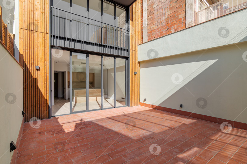 Скачать Солнечный вид на внутренний дворик отремонтированной квартиры в современном здании. Наружный фасад узкого современного дома в Барселоне, Испания фотосток Ozero