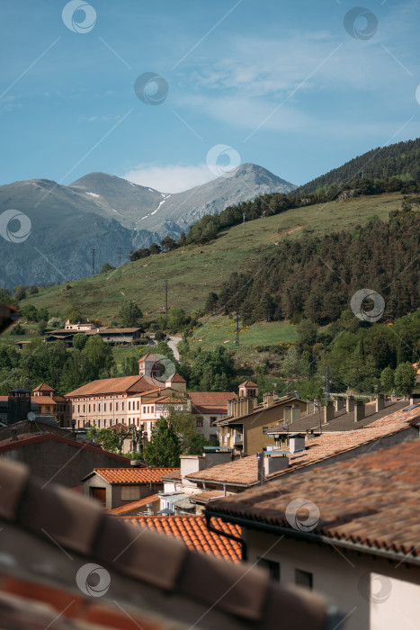 Скачать Оранжевые крыши современных домов в маленькой деревушке Рибес-де-Фрезер у подножия Пиренеев в Испании. Солнечный свет освещает красивую деревню с живописной горной природой и красивой архитектурой. фотосток Ozero