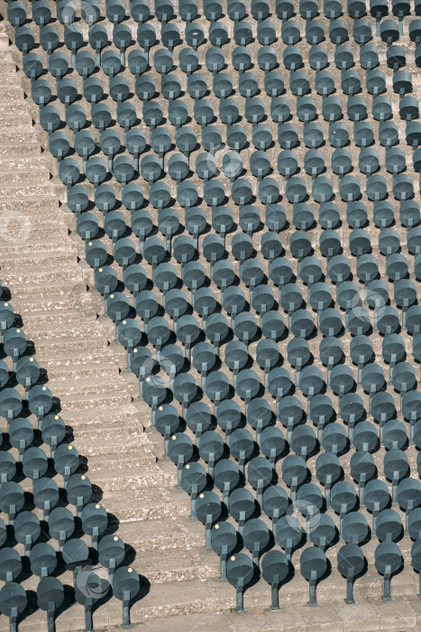 Скачать Пустые ряды новых удобных пластиковых стульев, прикрепленных к полу на пустом стадионе. Сиденье, предназначенное для спортивных арен. Каменная лестница спортивного стадиона делит стулья на сектора. фотосток Ozero