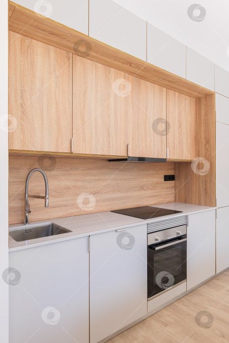 Скачать Современная кухня с деревянной мебелью, серой столешницей и встроенной бытовой техникой в минималистском дизайне интерьера фотосток Ozero
