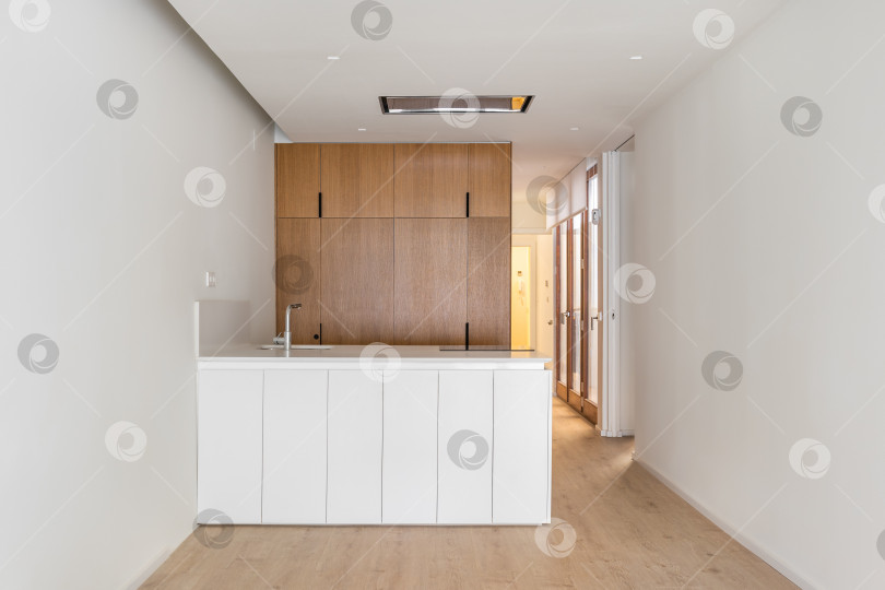 Скачать Интерьер белой кухни с деревянной мебелью и кухонным островом фотосток Ozero