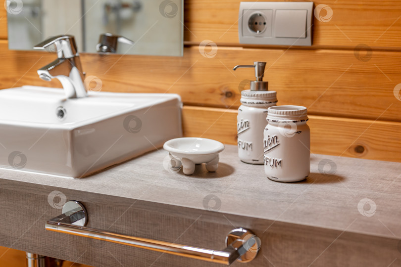 Скачать Держатель для зубной щетки и дозатор жидкого мыла рядом с раковиной в оформленной ванной комнате с деревянными стенами. фотосток Ozero