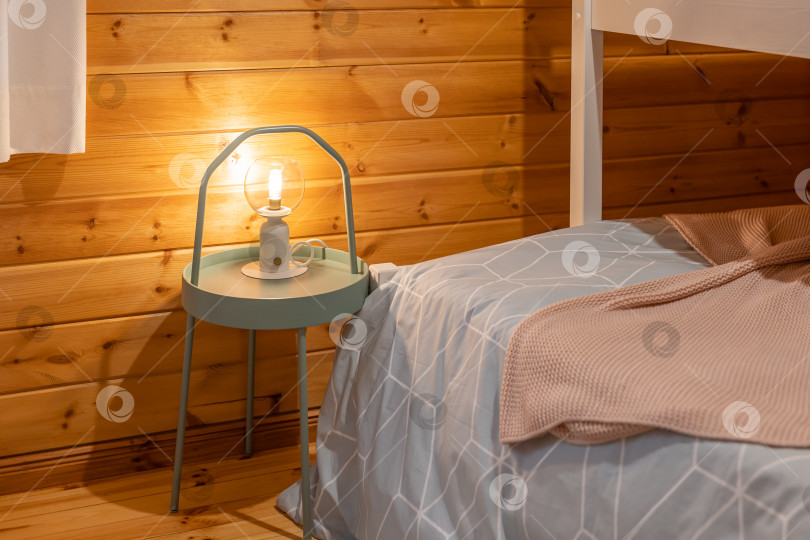 Скачать Крупным планом современная лампочка на ночном столике в спальне в деревянном интерьере комнаты. фотосток Ozero
