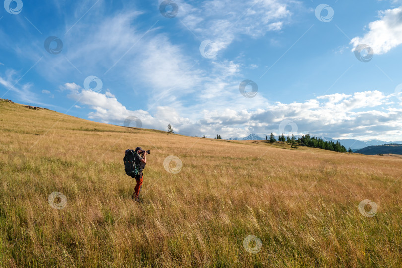 Скачать Фотограф-путешественник делает снимок альпийского нагорья. Одиночный поход. Путешественник-фрилансер, блогер lifestyle, концепция приключенческого путешествия на открытом воздухе. фотосток Ozero