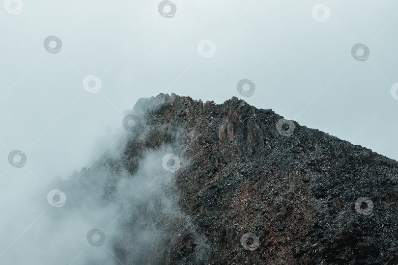 Скачать Ужасные горные тени. Драматический туман среди гигантских скалистых гор. Призрачный атмосферный вид на большой утес. Низкие облака и красивые скалистые горы. Минималистичный пейзаж таинственного места. фотосток Ozero