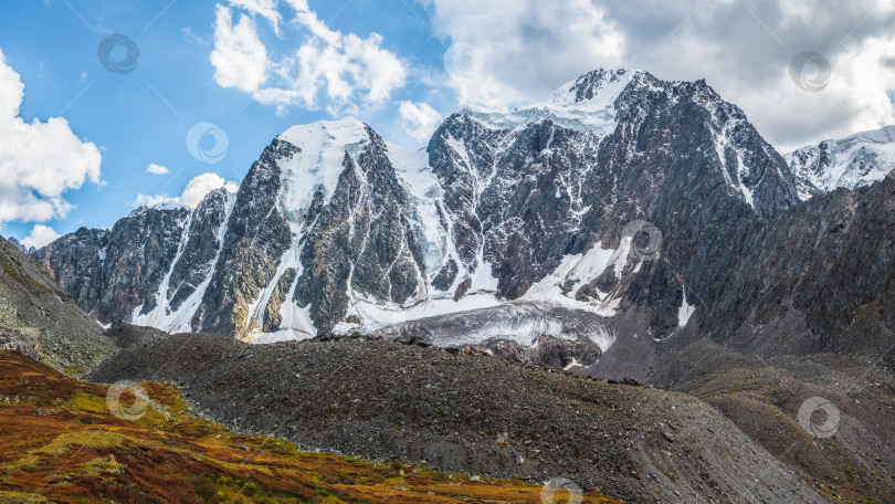 Скачать Атмосферный альпийский пейзаж с массивным висячим ледником на заснеженной горной вершине. Большой балконный серак на краю ледника. Голубое облачное небо над заснеженными горами. Величественный пейзаж на большой высоте. фотосток Ozero