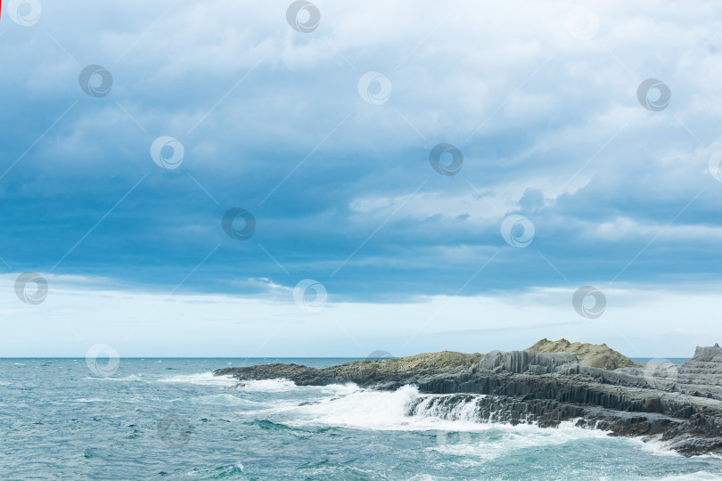 Скачать скалистый берег моря, образованный столбчатым базальтом на фоне штормового моря, прибрежный пейзаж Курильских островов фотосток Ozero
