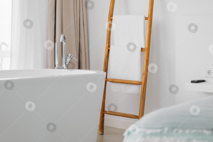 Скачать Современный интерьер спальни отеля с ванной комнатой, металлическим краном и белыми полотенцами на декоративной деревянной лестнице. фотосток Ozero