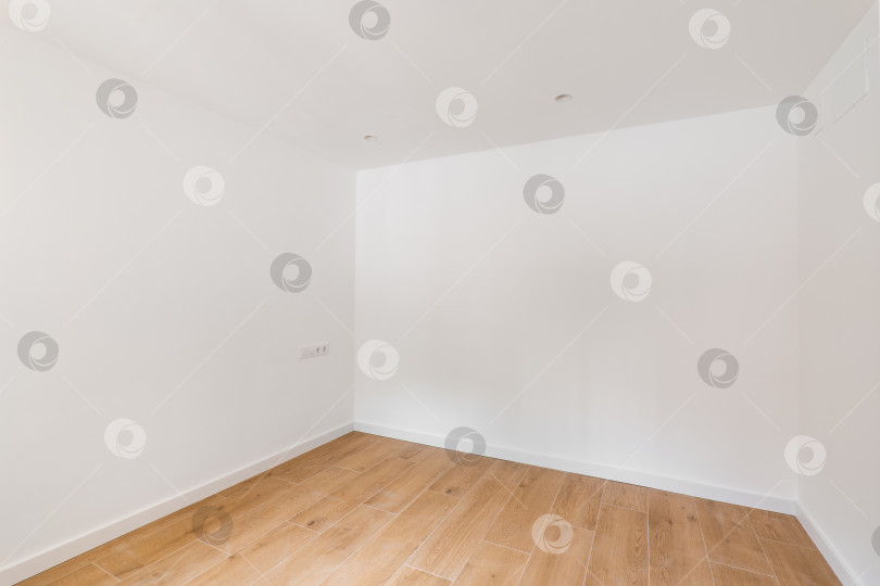 Скачать Пустая комната с ламинатным полом и недавно покрашенными в белый цвет стенами в отремонтированной квартире. Концепция ремонта и строительства. фотосток Ozero
