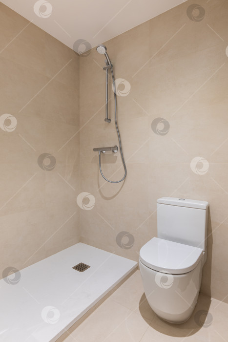 Скачать Ванная комната с туалетом, душем и стеной, выложенной керамической плиткой. Вертикальный вид современного минималистского интерьера фотосток Ozero