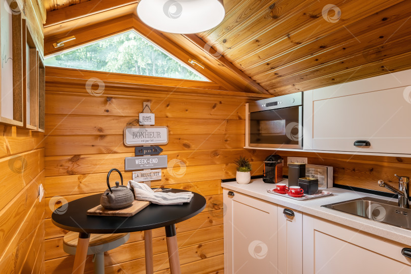 Скачать Компактная кухня с небольшим круглым обеденным столом в деревянном доме. Концепция деревенской жизни. фотосток Ozero