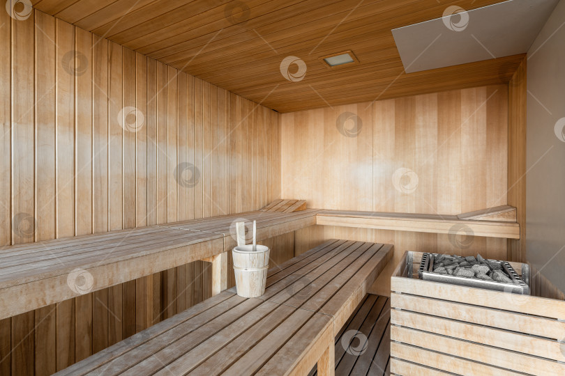 Скачать Классический деревянный интерьер финской сауны со скамейками и шезлонгами, аксессуарами для горячих процедур. фотосток Ozero