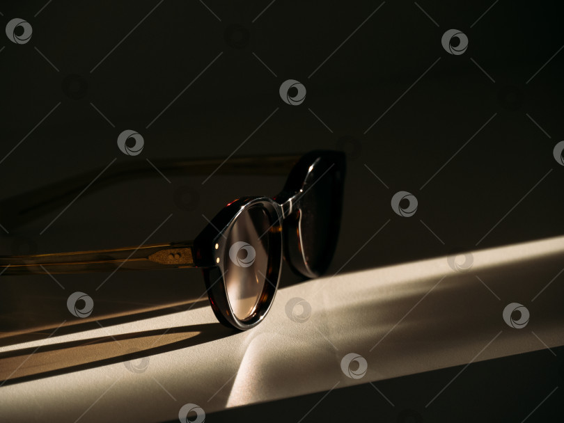 Скачать Солнцезащитные очки трендовой формы на столе в лучах прекрасного утреннего солнца. фотосток Ozero