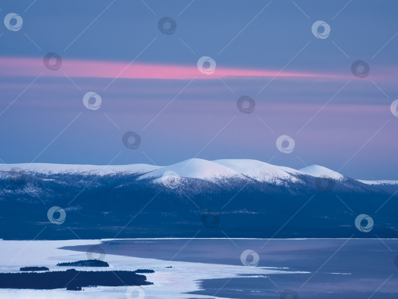 Скачать Заснеженные холмы полярного конуса зимой ранним утром. Зимний полярный пейзаж. Вид на заснеженные холмы и Белое море. Холодная зимняя погода. Суровый северный климатический фон. фотосток Ozero