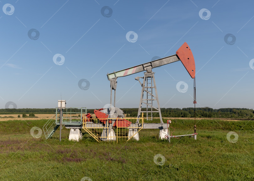 Скачать Действующая нефтяная и газовая скважина на нефтяном месторождении, изображенная на фоне голубого неба фотосток Ozero