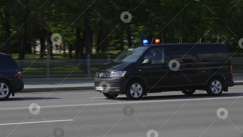 Скачать МОСКВА - 24 июля 2019 года: Черный правительственный автомобиль с сиреной и мигалками проезжает через перекресток 24 июля 2019 года в Москве, Россия фотосток Ozero