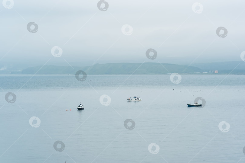 Скачать рыбацкие лодки в море на фоне далекого туманного побережья фотосток Ozero