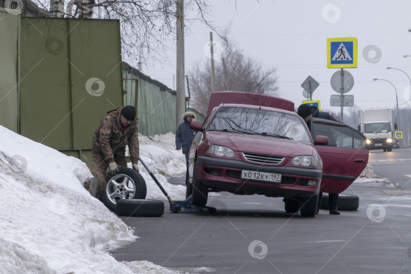 Скачать МОСКВА, РОССИЯ - 02 ноября 2019 года : Автомеханик работает в гараже и меняет легкосплавную шину на колесе фотосток Ozero