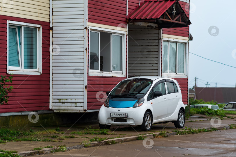Скачать малолитражный электромобиль Mitsubishi i-MiEV возле старого дома в приморской деревне фотосток Ozero