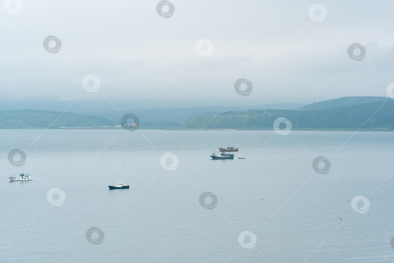 Скачать рыбацкие лодки в море на фоне далекого туманного побережья фотосток Ozero