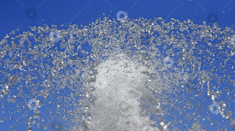 Скачать Фонтанные капли чистой воды на фоне голубого неба. фотосток Ozero