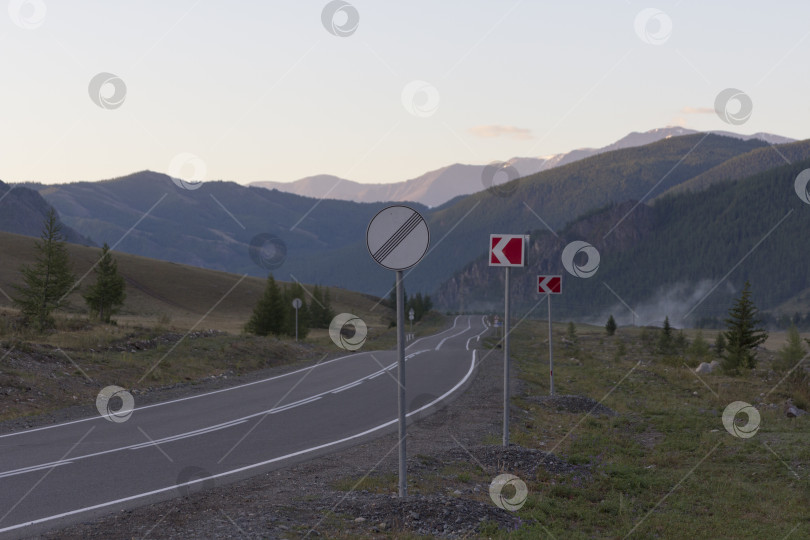 Скачать Кинематографический пейзаж: дорога, уходящая в горы ранним утром фотосток Ozero