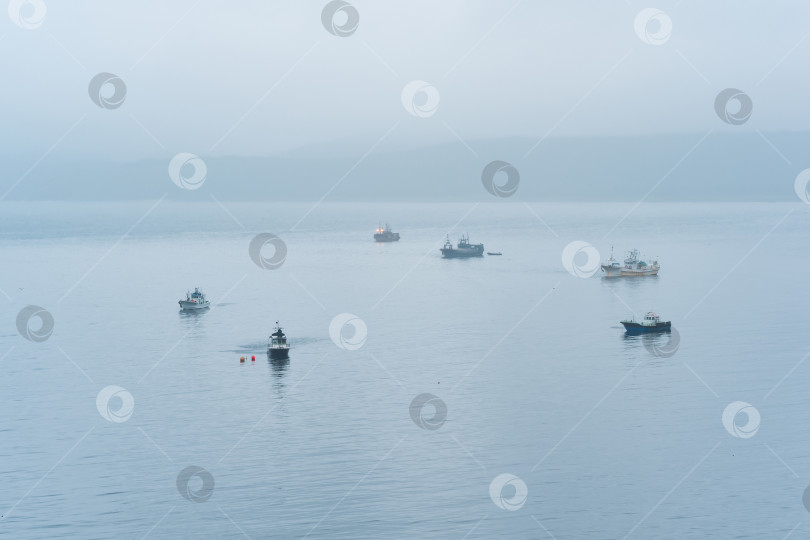 Скачать рыбацкие лодки в море на фоне далекого туманного побережья фотосток Ozero