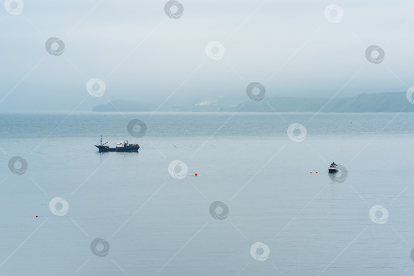 Скачать рыбацкие лодки в море на фоне далекого туманного побережья фотосток Ozero