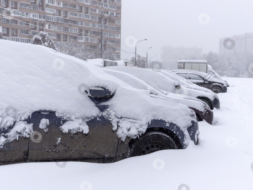 Скачать Транспортные средства, занесенные снегом во время зимней метели на парковке фотосток Ozero