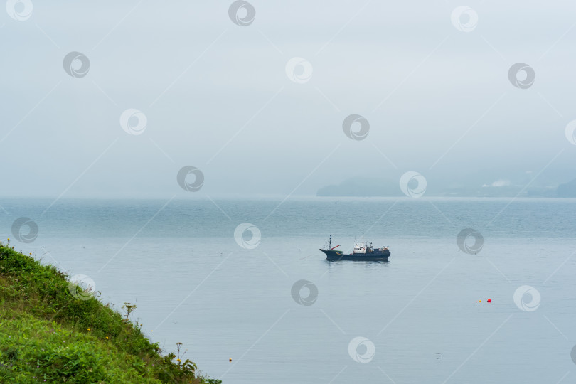 Скачать рыбацкая лодка в море на фоне далекого туманного побережья фотосток Ozero