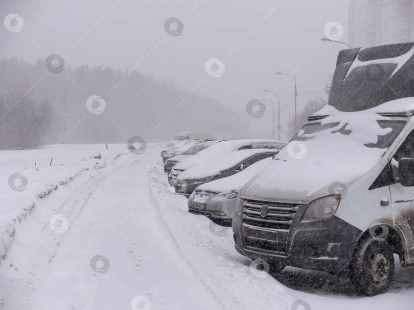 Скачать Транспортные средства, занесенные снегом во время зимней метели на парковке фотосток Ozero