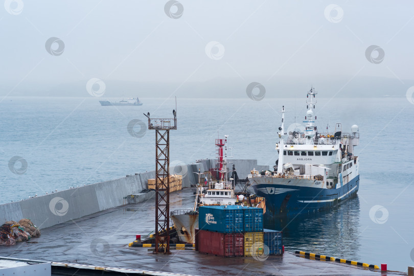 Скачать рыбацкая лодка у причала в гавани на берегу облачного моря фотосток Ozero