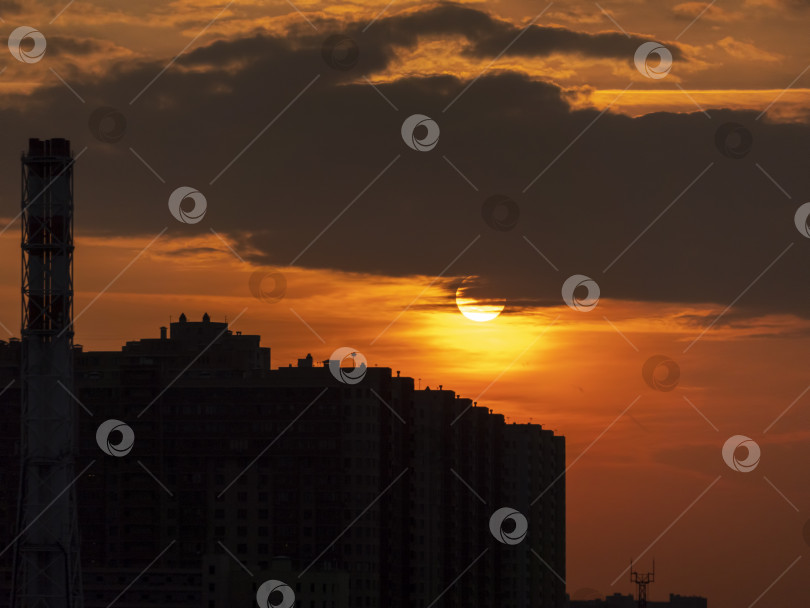 Скачать Закат в большом городе между зданиями и опорами электропередачи в тени на фоне большого солнца фотосток Ozero