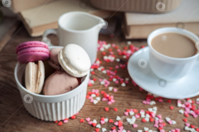 Скачать Миндальное печенье в миске, чашка кофе, молочник на фоне маленьких сердечек на деревянном фоне фотосток Ozero