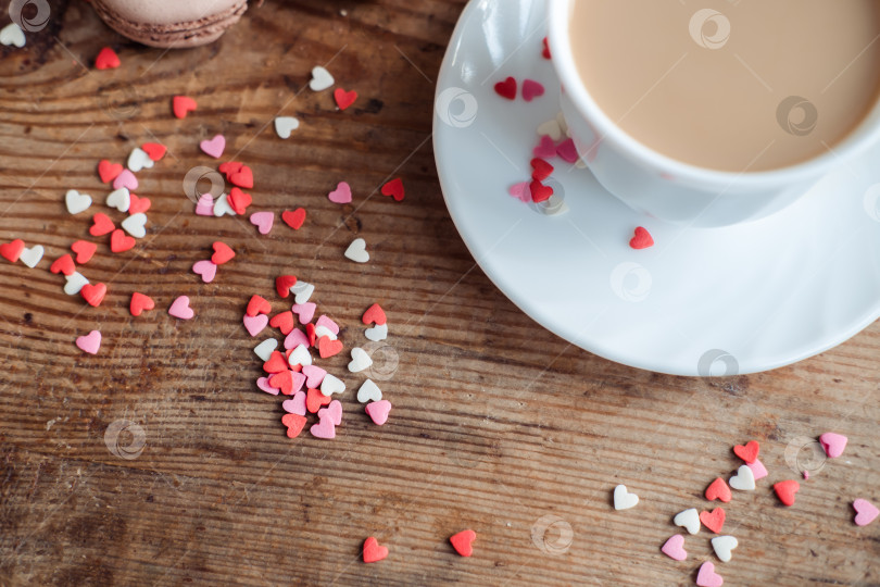 Скачать Кофе в белой чашке стоит на деревянном фоне, усыпанном сердечками фотосток Ozero