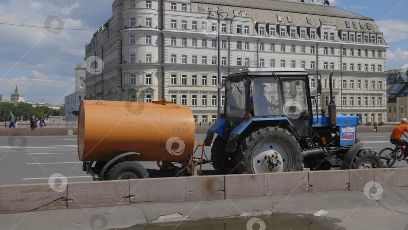 Скачать МОСКВА - 7 мая: Синий трактор с оранжевым баком для полива улиц. 7 мая 2017 года в Москве, Россия. фотосток Ozero