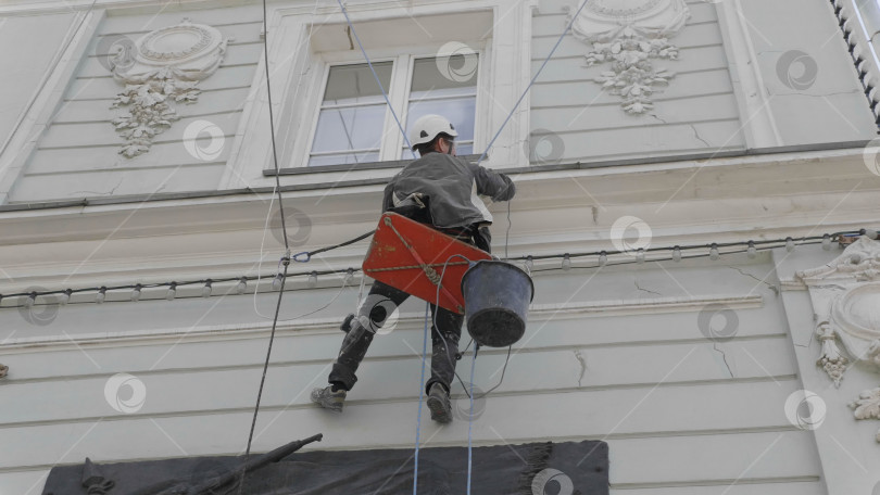 Скачать МОСКВА - 7 июня: Альпинист проводит ремонтные работы на высоте многоэтажного здания 7 июня 2017 года в Москве, Россия. фотосток Ozero