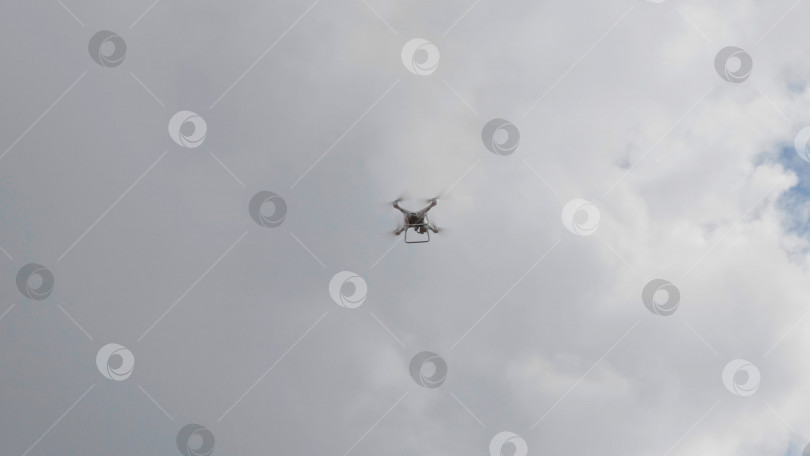 Скачать Летящий вертолет-дрон на фоне белых облаков фотосток Ozero