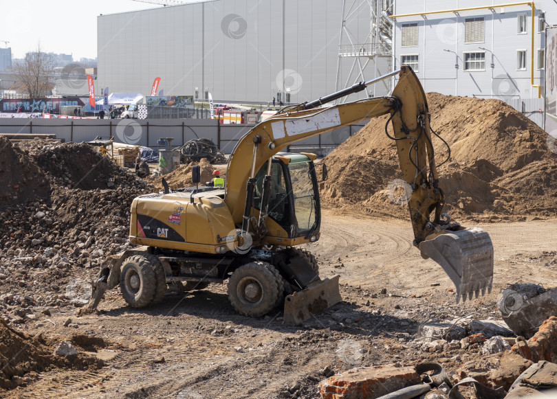 Скачать МОСКВА, РОССИЯ - 27 мая 2022 года: строительный экскаватор желтого цвета на строительной площадке в карьере для добычи полезных ископаемых фотосток Ozero
