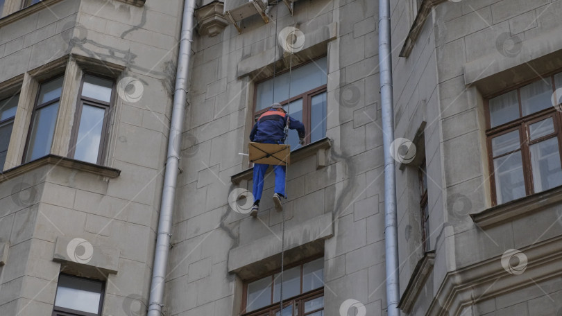 Скачать МОСКВА - 26 августа: Альпинист проводит ремонтные работы на высоте многоэтажного здания 26 августа 2017 года в Москве, Россия фотосток Ozero