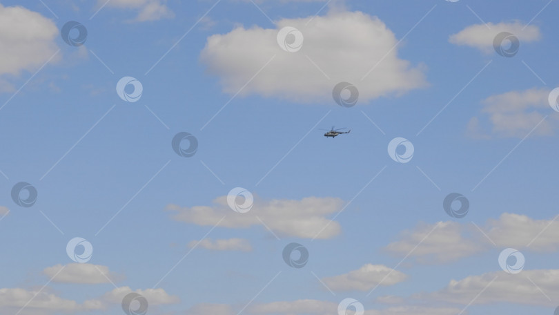 Скачать Вертолет зеленого цвета летит на фоне белых облаков фотосток Ozero