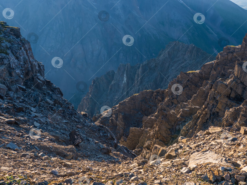 Скачать Опасный горный кулуар. Красочный солнечный пейзаж с утесами, большими скалистыми горами и эпическим глубоким ущельем. фотосток Ozero