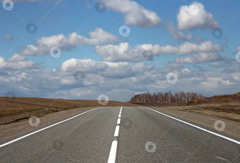 Скачать Асфальтированная дорога и облака на голубом небе в солнечный день фотосток Ozero