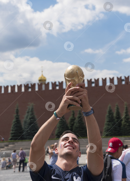 Скачать МОСКВА - 26 июня 2018 года: Фанаты Чемпионата мира по футболу во Франции держат кубок в своих типичных костюмах на улицах 26 июня 2018 года в Москве, Россия фотосток Ozero