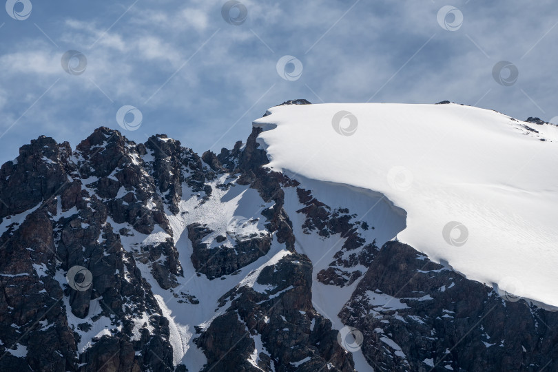 Скачать Снежный выступ на вершине горы. Уступы заснеженных гор. Утесы и большие скалы. Опасная местность. фотосток Ozero